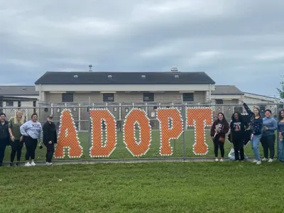 Volunteers near Adopt fence sign